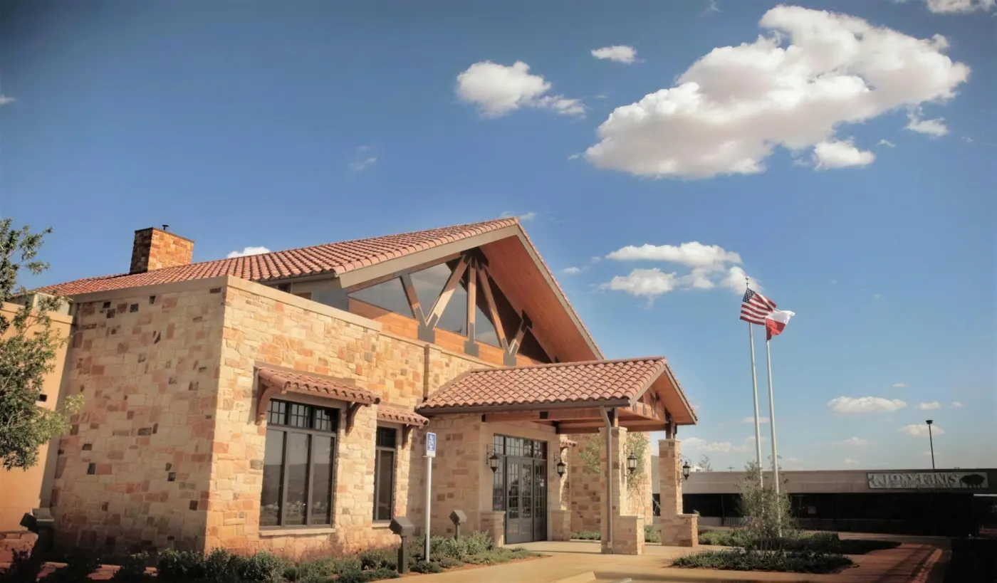 A stone and timber bank building with a red tile roof under a blue sky.